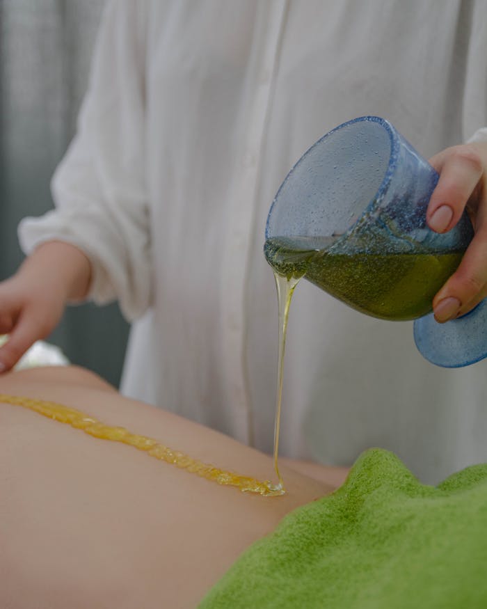 Close-up of a soothing massage oil being poured onto a person's back for relaxation therapy.